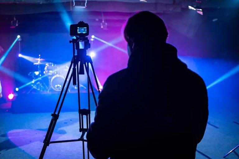 A camera man setting up his camera and video equipment to record a concert.